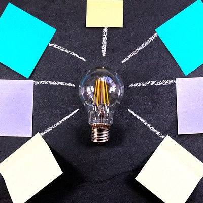 Lightbulb with colorful sticky notes on chalkboard